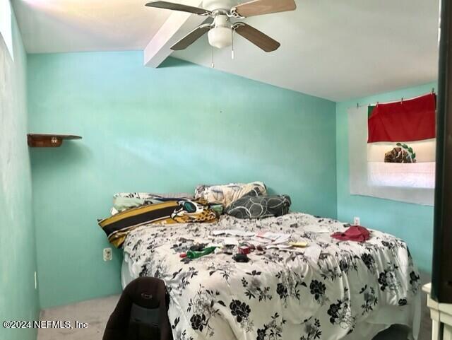 bedroom with ceiling fan and beam ceiling