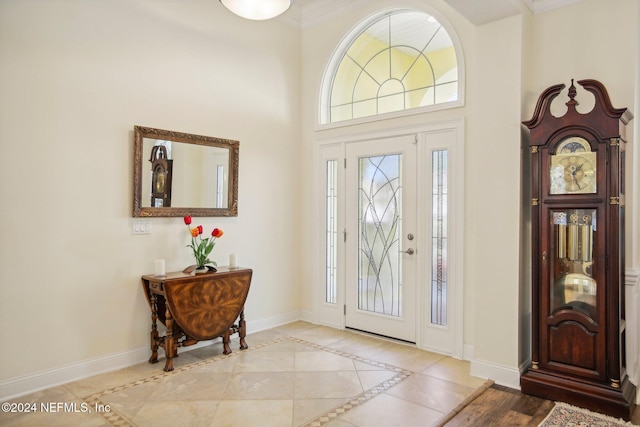 foyer with a towering ceiling, crown molding, and light tile patterned floors