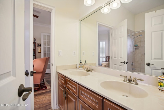 bathroom with a tile shower, hardwood / wood-style flooring, vanity, and ornamental molding