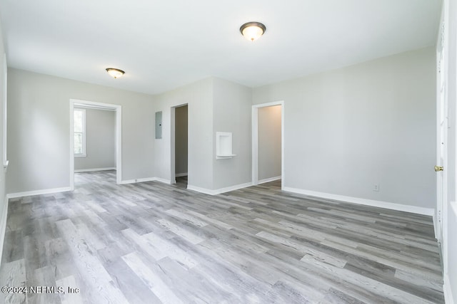 spare room featuring electric panel and light hardwood / wood-style flooring