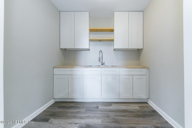 interior space with white cabinets, dark wood-type flooring, and sink