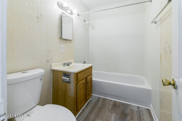 full bathroom featuring vanity, hardwood / wood-style flooring, toilet, tile walls, and tub / shower combination