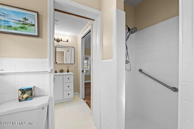 bathroom featuring a tile shower, tile patterned floors, vanity, and toilet