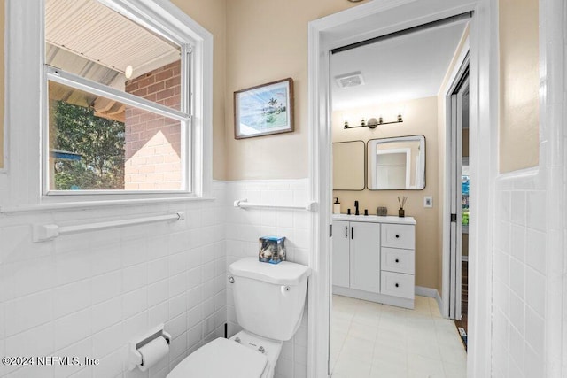 bathroom featuring tile patterned floors, vanity, tile walls, and toilet