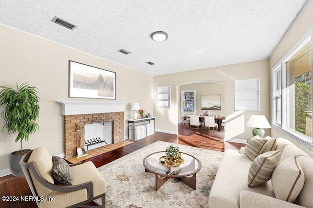 living room with a fireplace, wood-type flooring, and a textured ceiling