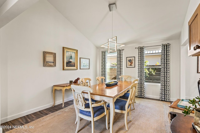 dining area with a notable chandelier, wood-type flooring, and high vaulted ceiling