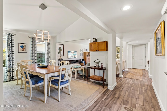 dining space featuring a chandelier, vaulted ceiling, and light hardwood / wood-style flooring