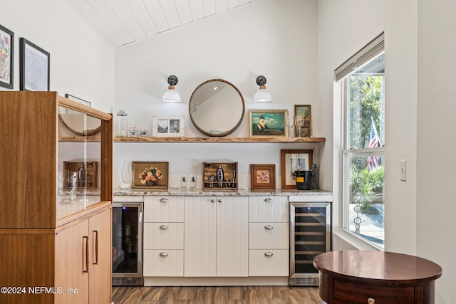 bar featuring white cabinets, light hardwood / wood-style floors, beverage cooler, and vaulted ceiling