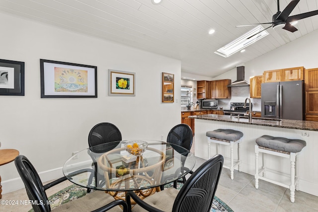 dining space with vaulted ceiling with skylight, ceiling fan, sink, light tile patterned floors, and wooden ceiling