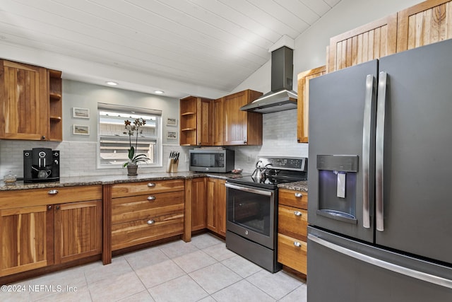 kitchen featuring stone counters, wall chimney exhaust hood, stainless steel appliances, vaulted ceiling, and light tile patterned floors