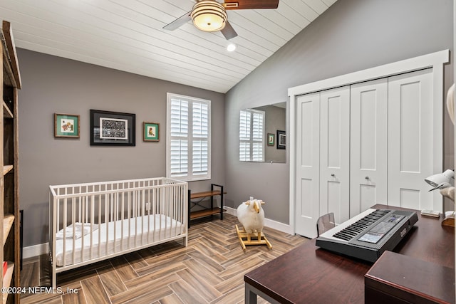 bedroom with lofted ceiling, ceiling fan, parquet flooring, a crib, and a closet