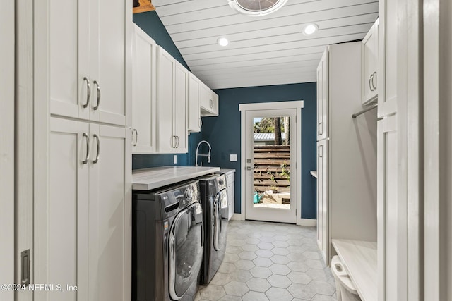 clothes washing area featuring washer and dryer, sink, cabinets, light tile patterned floors, and wood ceiling