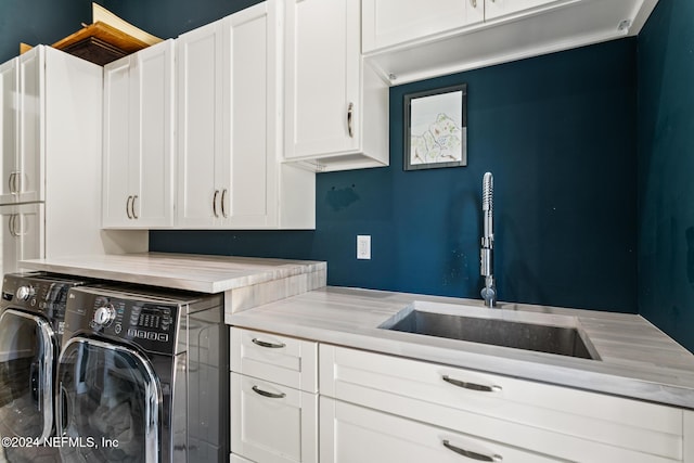 laundry room with washing machine and clothes dryer, sink, and cabinets