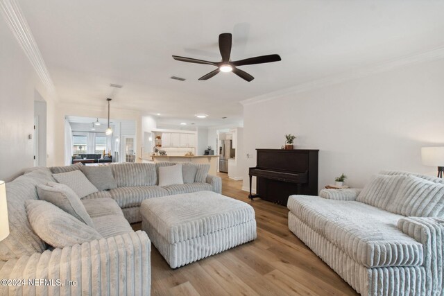 living room featuring light wood-type flooring, ceiling fan, and ornamental molding