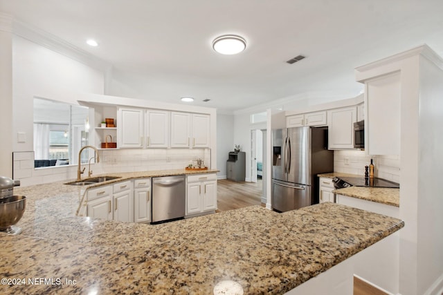 kitchen with white cabinetry, stainless steel appliances, tasteful backsplash, kitchen peninsula, and light hardwood / wood-style floors