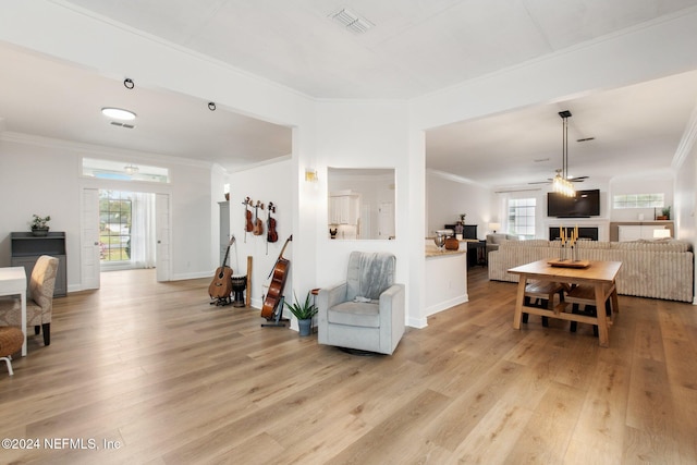 living room with light hardwood / wood-style floors, ceiling fan, and ornamental molding