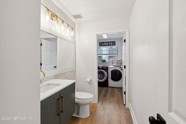 bathroom with washer and dryer, vanity, hardwood / wood-style flooring, and toilet