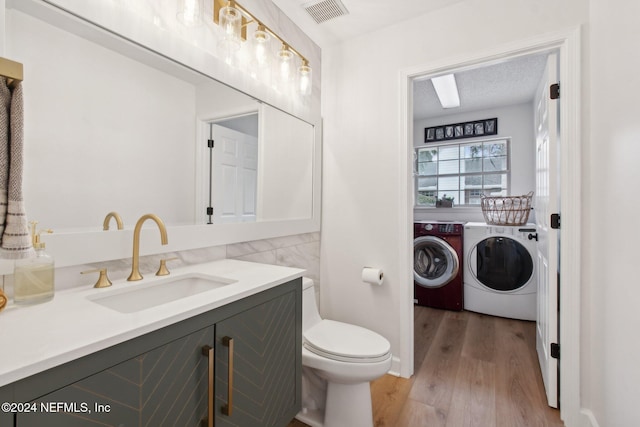 bathroom with a textured ceiling, toilet, vanity, washer and dryer, and hardwood / wood-style flooring