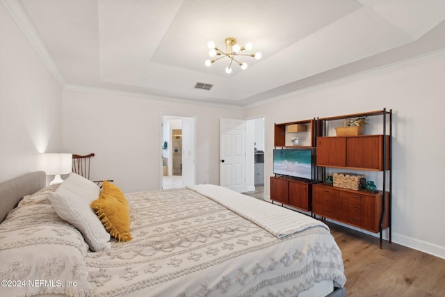 bedroom featuring a raised ceiling, dark hardwood / wood-style flooring, ornamental molding, and a chandelier