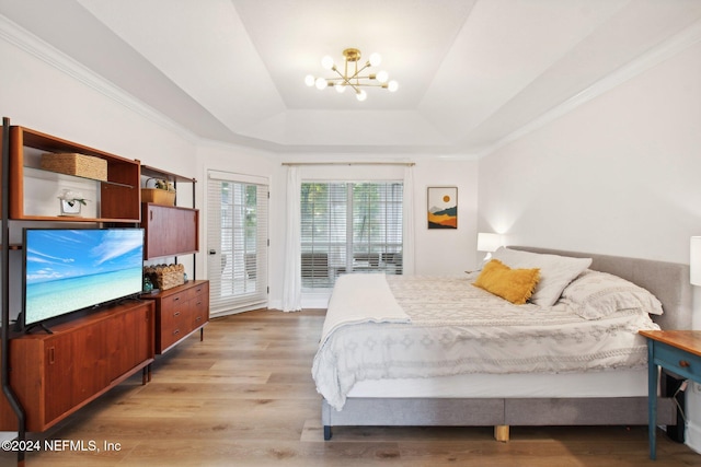 bedroom featuring access to exterior, a raised ceiling, light hardwood / wood-style flooring, a notable chandelier, and crown molding