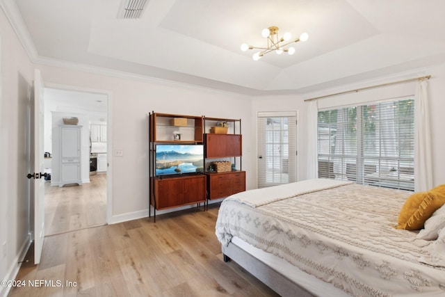 bedroom with a tray ceiling, ornamental molding, a notable chandelier, and light wood-type flooring