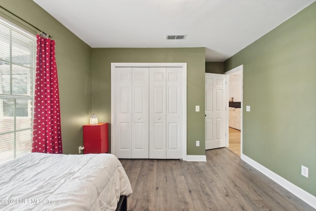 bedroom with hardwood / wood-style flooring, a closet, and multiple windows