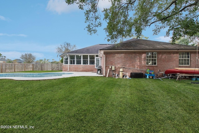 rear view of property featuring a yard, a fenced in pool, and a sunroom