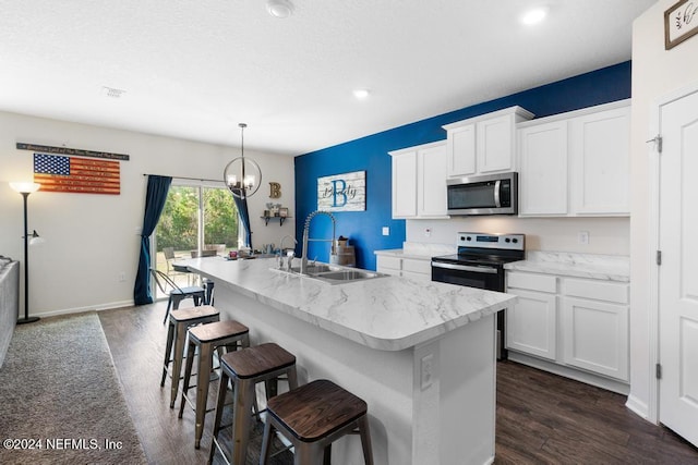 kitchen featuring pendant lighting, dark wood-type flooring, an island with sink, white cabinetry, and stainless steel appliances