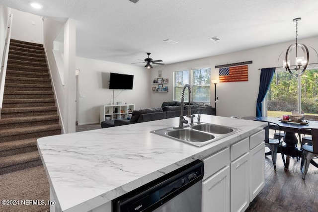 kitchen with white cabinetry, sink, stainless steel dishwasher, an island with sink, and ceiling fan with notable chandelier