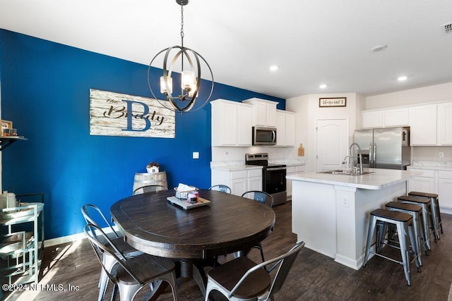 kitchen featuring white cabinets, dark wood-type flooring, an island with sink, and stainless steel appliances