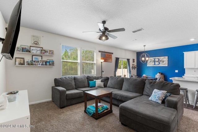 carpeted living room featuring ceiling fan with notable chandelier and a textured ceiling