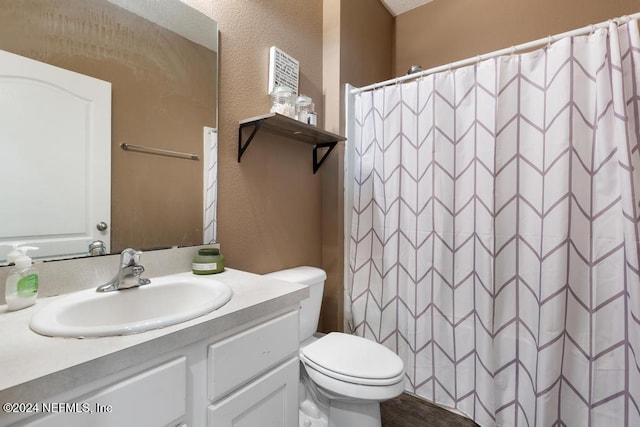 bathroom with hardwood / wood-style floors, vanity, toilet, and walk in shower