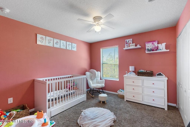 carpeted bedroom featuring a textured ceiling, a nursery area, a closet, and ceiling fan