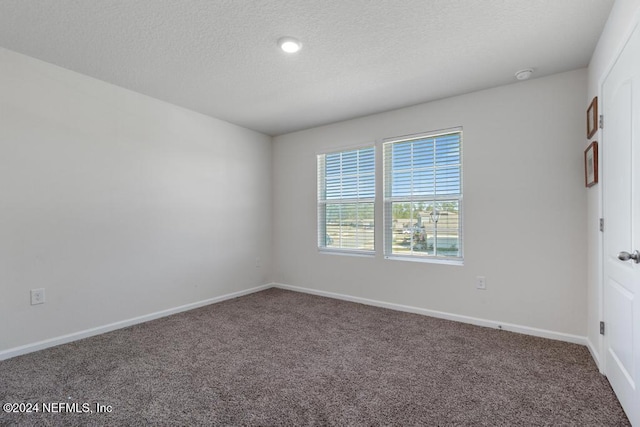 carpeted empty room featuring a textured ceiling