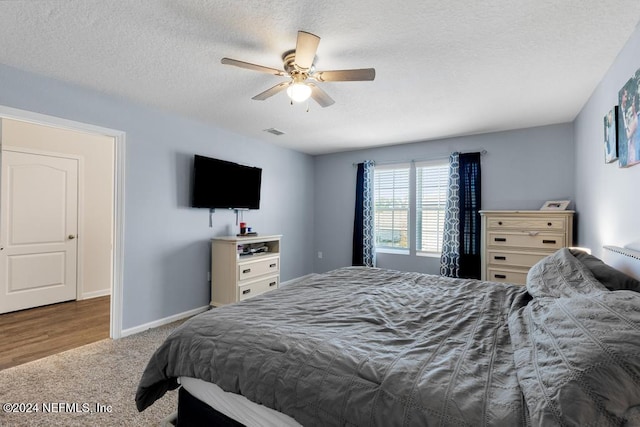 bedroom featuring ceiling fan, hardwood / wood-style floors, and a textured ceiling