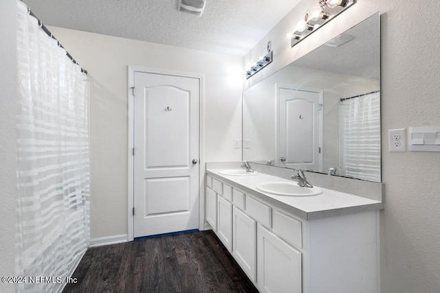 bathroom with hardwood / wood-style floors, vanity, and a textured ceiling