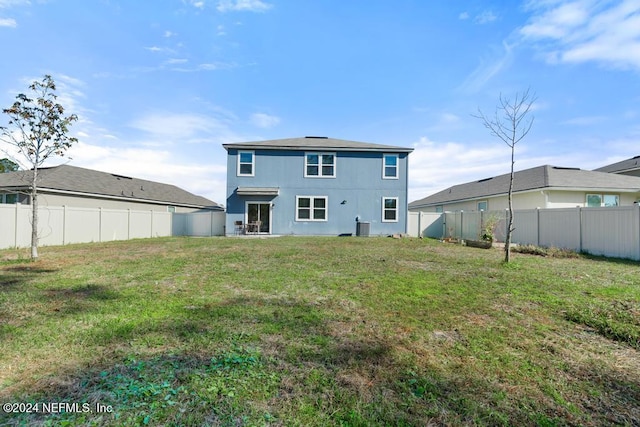 rear view of property featuring a lawn and central AC