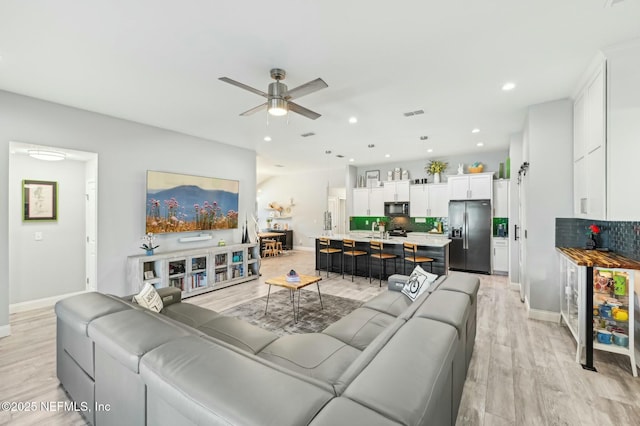 living area featuring visible vents, baseboards, a ceiling fan, light wood-style flooring, and recessed lighting