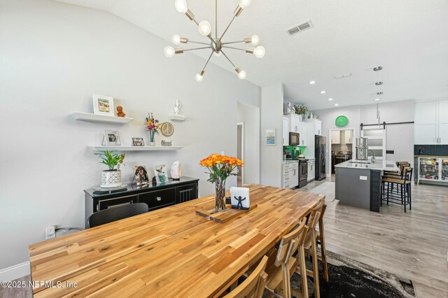 dining room with recessed lighting, visible vents, vaulted ceiling, light wood finished floors, and an inviting chandelier