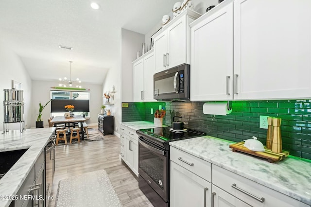 kitchen with stainless steel appliances, light wood-type flooring, white cabinets, and vaulted ceiling