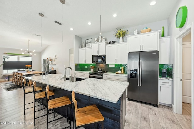 kitchen featuring stainless steel appliances, visible vents, decorative backsplash, a kitchen island with sink, and a sink