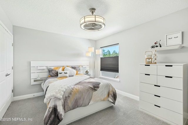 bedroom featuring baseboards, a textured ceiling, and light colored carpet