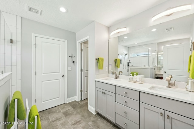 bathroom featuring double vanity, a stall shower, a sink, and visible vents