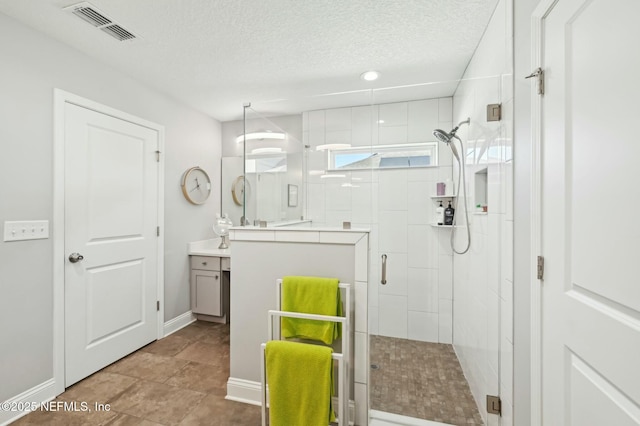 full bathroom featuring a stall shower, visible vents, vanity, and a textured ceiling