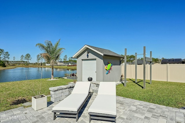 view of patio with an outbuilding, a water view, fence, and a storage unit