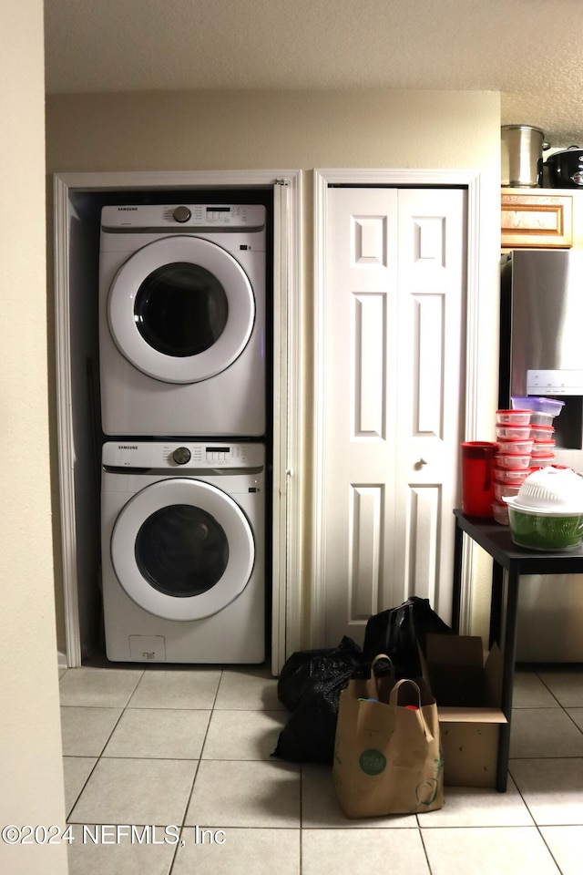 washroom with light tile patterned flooring and stacked washer and dryer