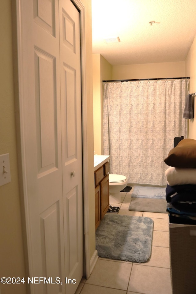 bathroom featuring tile patterned flooring, vanity, toilet, and a textured ceiling