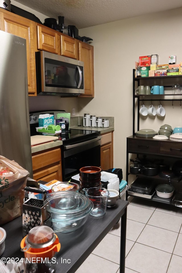 kitchen with light tile patterned flooring, stainless steel appliances, and a textured ceiling