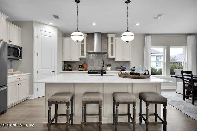 1040 Creighton Rd, Fleming Island, FL 32003 - kitchen featuring wall chimney range hood, a sink, stainless steel appliances, tasteful backsplash, and light wood-style floors