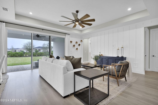 living room featuring light wood-type flooring and a tray ceiling